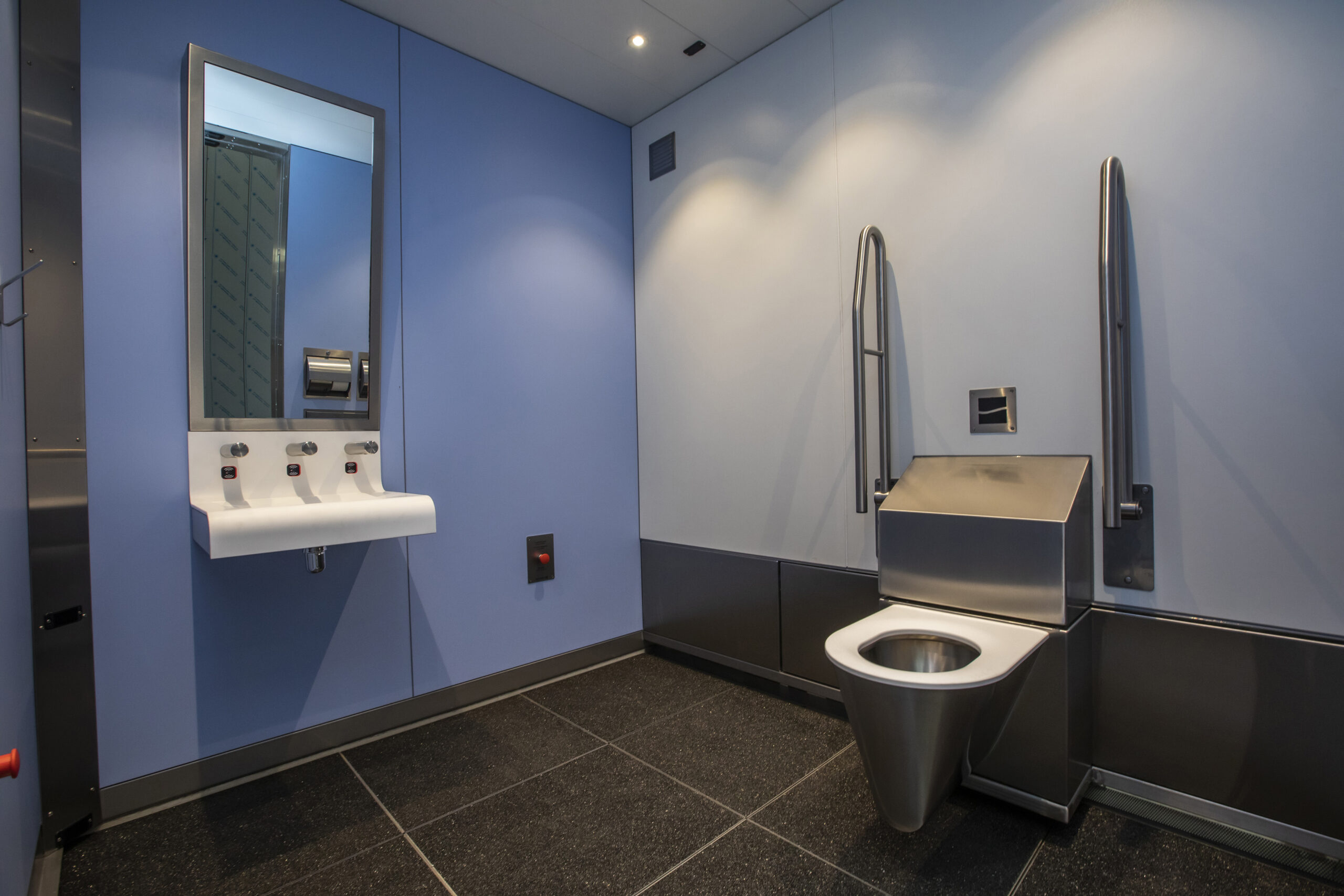 Inside wheelchair-accessible revolving toilet unit with mirror and solid shape washbasin  